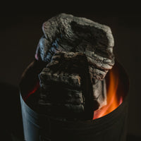 Stack of gray charcoal in a black container with a dark background