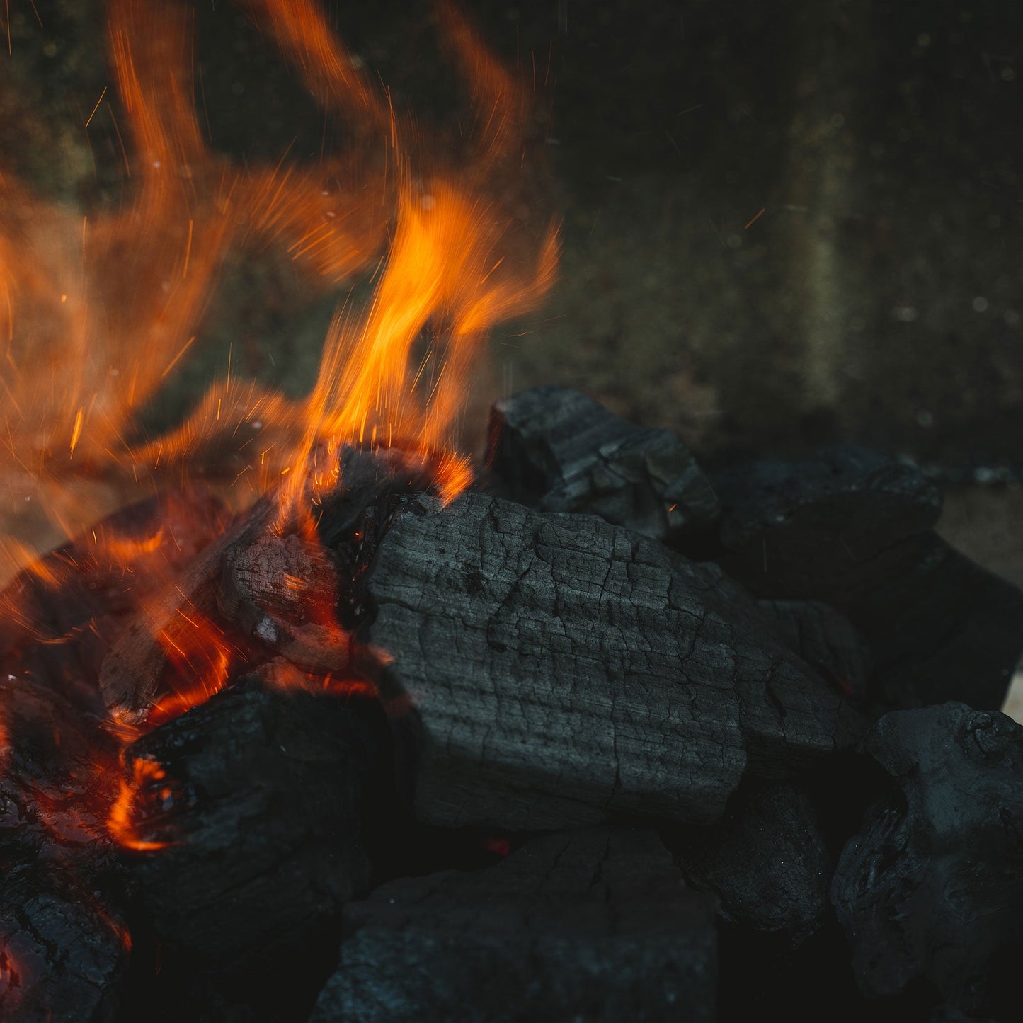 Close-up of burning coals with flames in a dark setting