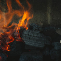 Close-up of burning coals with flames in a dark setting